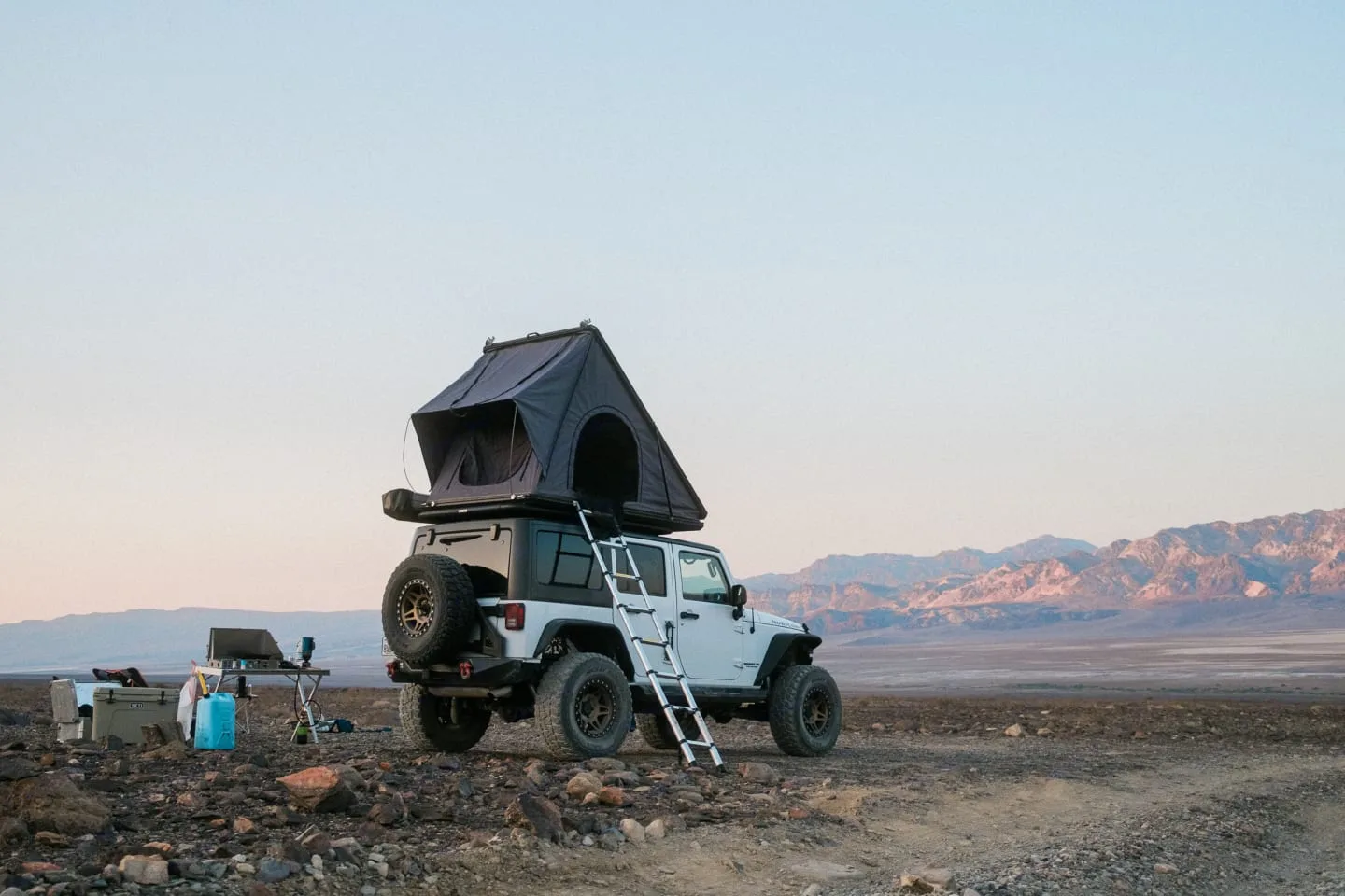 Jeep Rubicon with rooftop tent popped up at sunrise in the desert