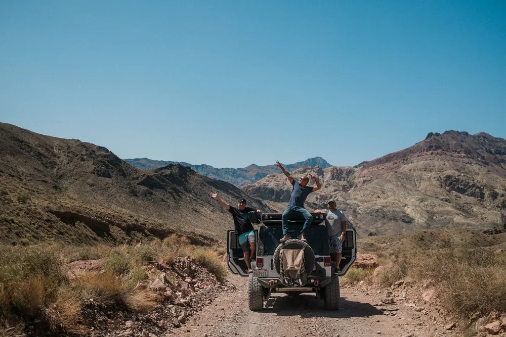 Renters celebrating from the back of the Jeep on a remote desert trail